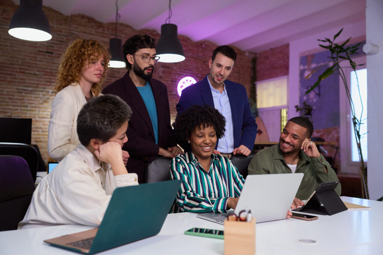 Diverse business team collaborating on project using laptop in modern office